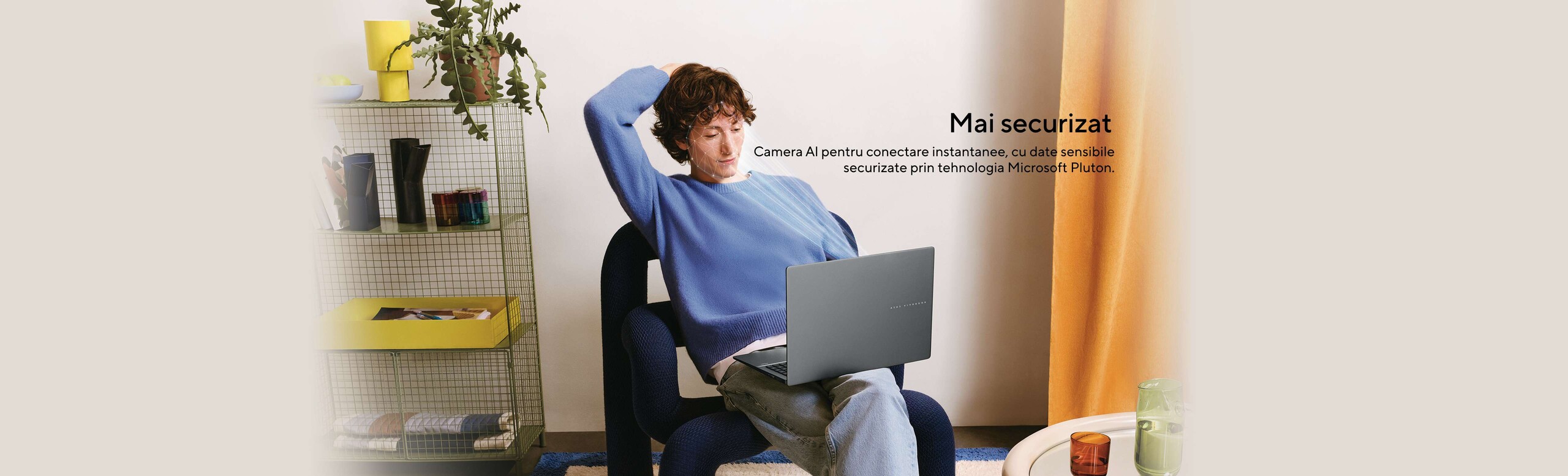 Baiat care sta pe scaun cu laptop ASUS orientat cu spatele si simuleaza autentificarea Hello faciala prin camera AI