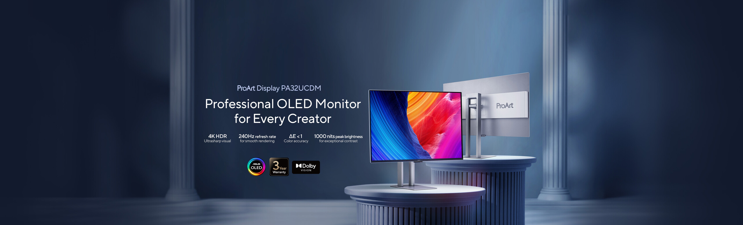 Două monitoare OLED ProArt afișate pe piedestaluri rotunde elegante, cu grafică abstractă colorată. Fundalul prezintă coloane impunătoare, creând o ambianță profesională și artistică.